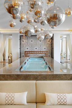 a living room filled with furniture and lots of hanging ornaments on the ceiling over a swimming pool