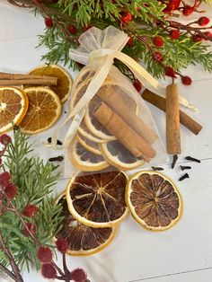 orange slices, cinnamon sticks and spices are on the table next to some christmas decorations