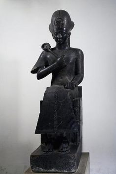 an ancient statue is displayed on a pedestal in front of a white wall and floor