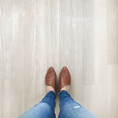 a woman's legs in jeans and heels standing on the floor with her feet up