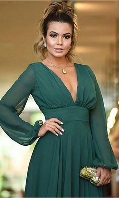 a woman in a green dress posing for the camera with her hands on her hips