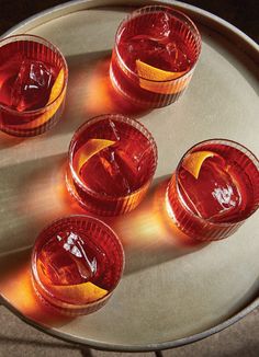 four shot glasses filled with red liquid on top of a metal tray