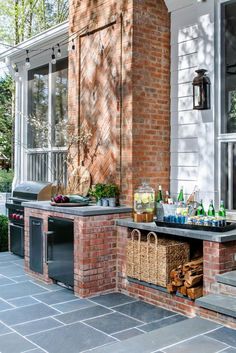 an outdoor bbq with bottles and drinks on the table next to it, in front of a brick building