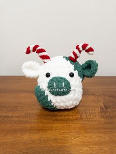 a crocheted stuffed animal with candy canes on its head sitting on a wooden table