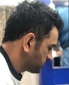 a close up of a person with a haircut in a barbershop looking at his phone