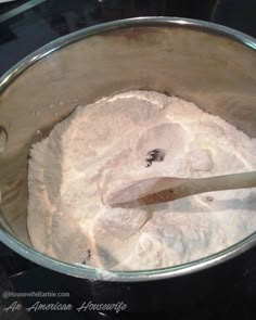 a metal bowl filled with white powder and a wooden spoon in the middle of it