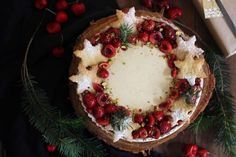 a tart with cherries and pine cones on top sits on a wooden table