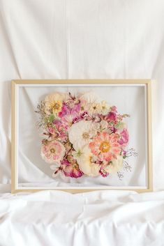 an arrangement of flowers in a wooden frame