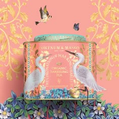 two birds are standing on top of a tin container with flowers and butterflies around it