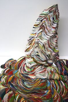 a large pile of multicolored paper sitting on top of a white floor next to a wall