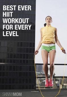 a woman in yellow shirt and green shorts holding a skipping rope while standing on top of a building