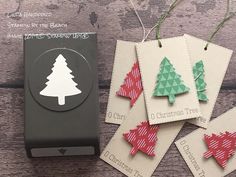 four tags with christmas trees on them are sitting next to a box and some string