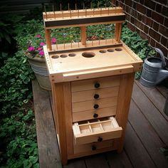 a wooden cabinet with drawers on top of it in front of some plants and flowers