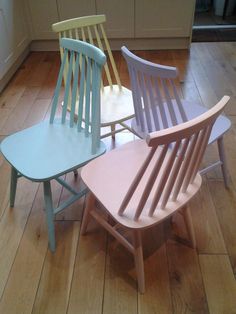 three wooden chairs sitting side by side on a hard wood floor in a kitchen area