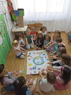 a group of children sitting on the floor in front of a white board with pictures