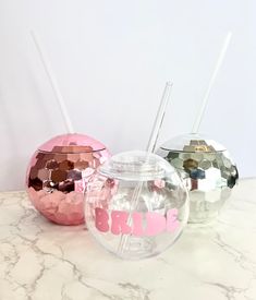 three different colored glass vases sitting on top of a marble counter next to each other