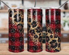 three red and gold glitter tumblers with straws in them on a wooden table