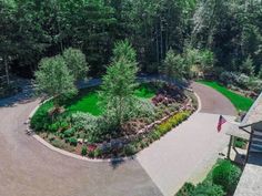 an aerial view of a driveway surrounded by trees and shrubs with a flag in the middle