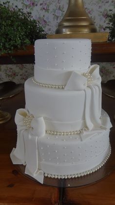 a white wedding cake with pearls and bows