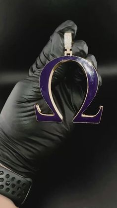 a gloved hand holding a purple and black object with the letter q on it