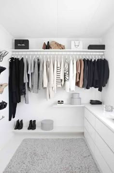 a white closet with clothes and shoes hanging on the wall next to a counter top