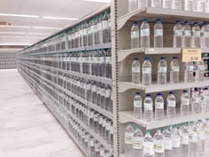 rows of bottled water are on shelves in a grocery store, with empty shelves behind them