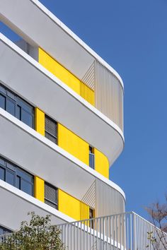 a building with yellow and white balconies against a blue sky in the background