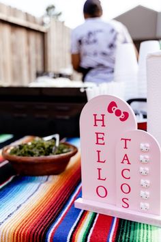 there is a sign that says hello taco's on the table next to a bowl of food