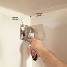 a man is painting the wall with paint rollers and an electrical outlet in his hand