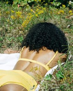 a woman laying on top of a towel in the grass