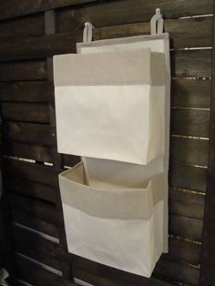 two white bags hanging on a wooden wall