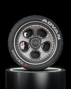 the front wheel of an automobile tire on a black pedestal with lights around it and red lettering