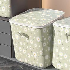 two storage bins with daisies on them sitting next to each other in a room