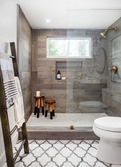 a white toilet sitting in a bathroom next to a walk in shower and wooden walls