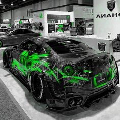 two cars parked in a showroom with green graphics on the front and side of them