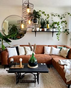 a living room filled with lots of plants next to a brown couch and coffee table