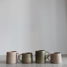 three mugs sitting on top of a table next to each other in front of a white wall