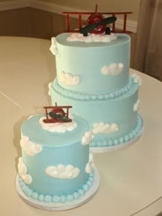 two blue cakes with airplanes on them sitting on a table