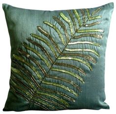 a green pillow with a fern leaf on it