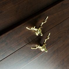 two brass deer figurines sitting on top of a wooden table