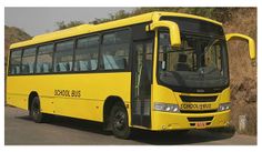 a yellow bus is parked on the side of the road next to some rocks and trees