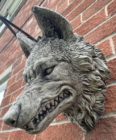 a statue of a wolf head on the side of a brick wall next to a window