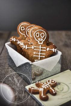 ginger cookies with white icing in a tin on a wooden table next to a card