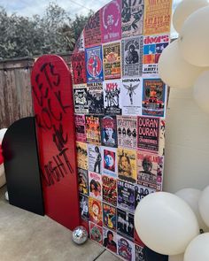 a red snowboard sitting on top of a cement ground next to balloons and white balls