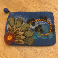 a blue purse with flowers on it sitting on a wooden floor next to a ball