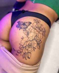 a woman's thigh with flowers and a butterfly tattoo on her lower back side