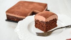 a piece of chocolate cake on a white plate with a fork next to the slice