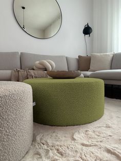 a living room filled with furniture and a large round mirror on the wall above it