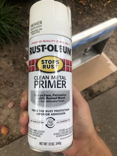 a hand holding a white spray can of rust - olen's stops and clean metal primer