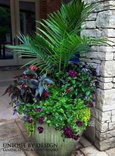 a large planter filled with lots of flowers next to a brick wall and door